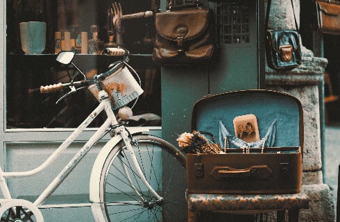 Antique bicycle and suitcases along with other items outside an antique store.
