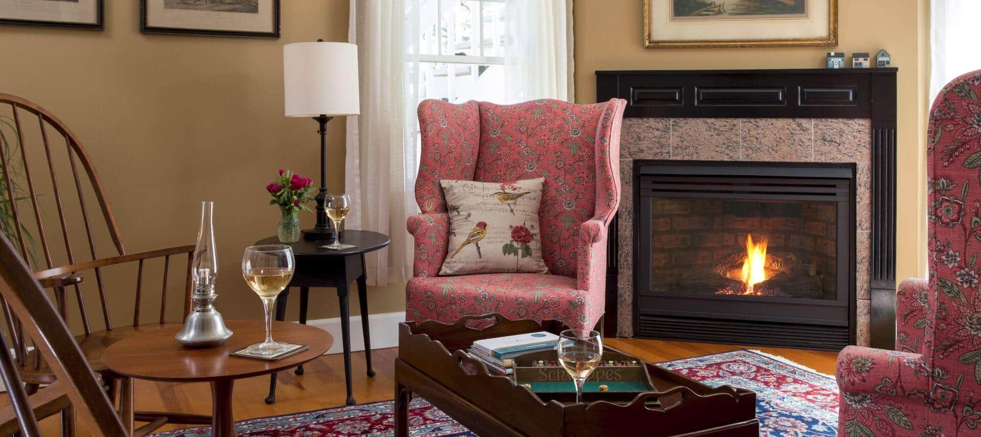 Sitting room area with rose wingback chairs and a fireplace.