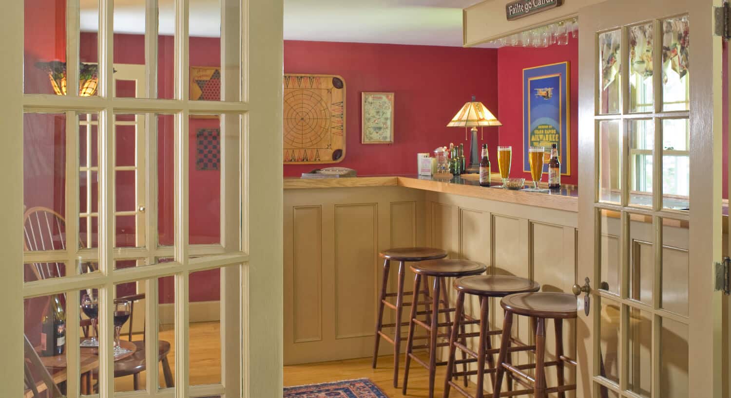 Tall bar with four stools in a room with red walls. 