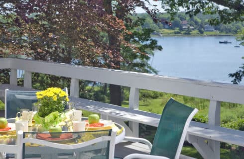 Small table and chairs on a deck set for breakfast.