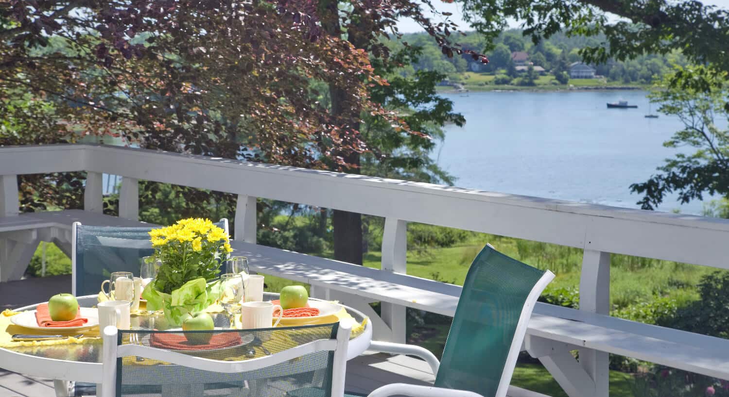 Small table and chairs on a deck set for breakfast.