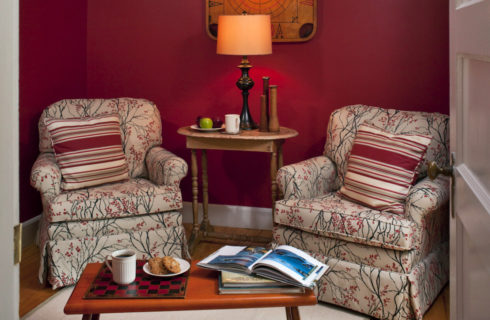 Cozy sitting area with overstuffed chairs, a side tabel with a lamp and a coffee table.