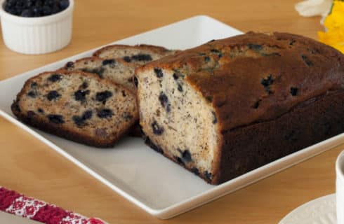 Blueberry quick bread cut into slices on a white plate.