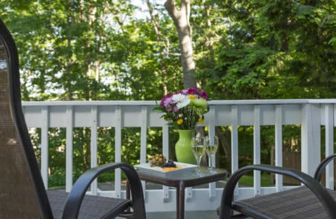 Small table and chairs on a deck with a white railing.