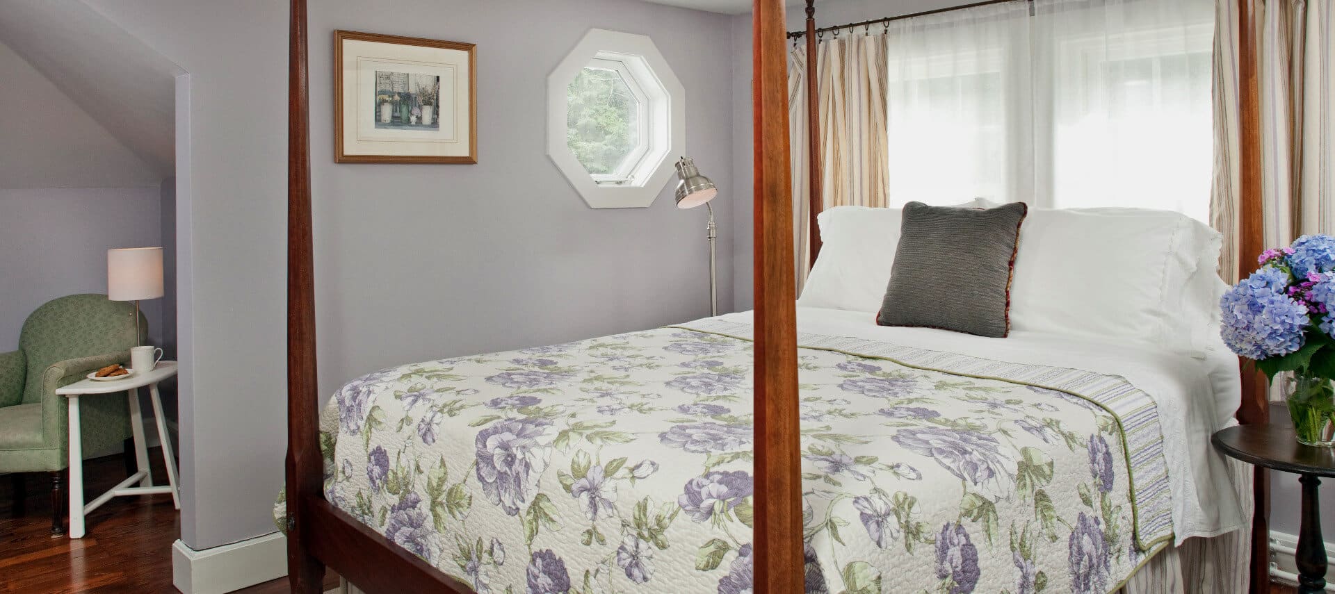 Bedroom painted in pale lavender with a cherry four-post bed made up in a lavender patterned cover.