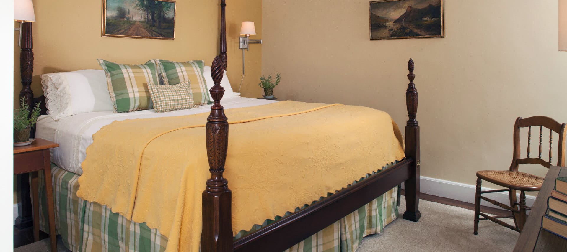 Large four-post wooden bed made up in clean linens in a roomw ith pale painted walls.