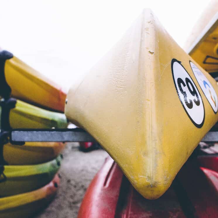 Red and yellow kayaks on a rack on the beach.