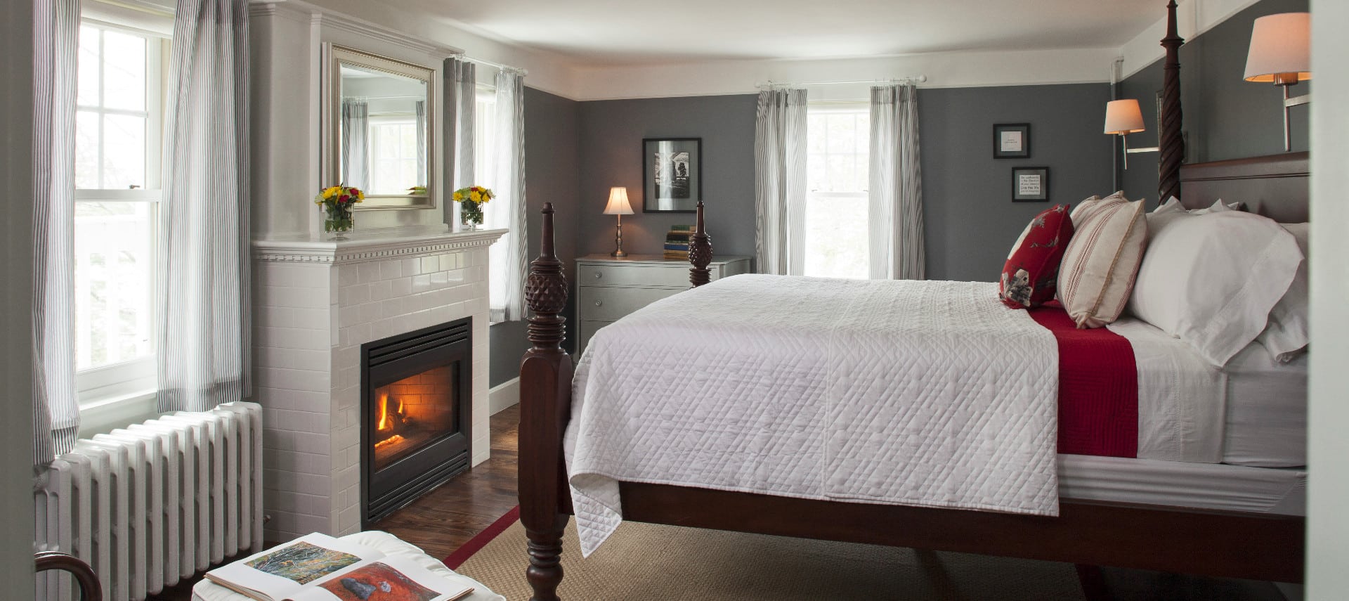 Large room with a fireplace and a wooden four-post bed made up in white