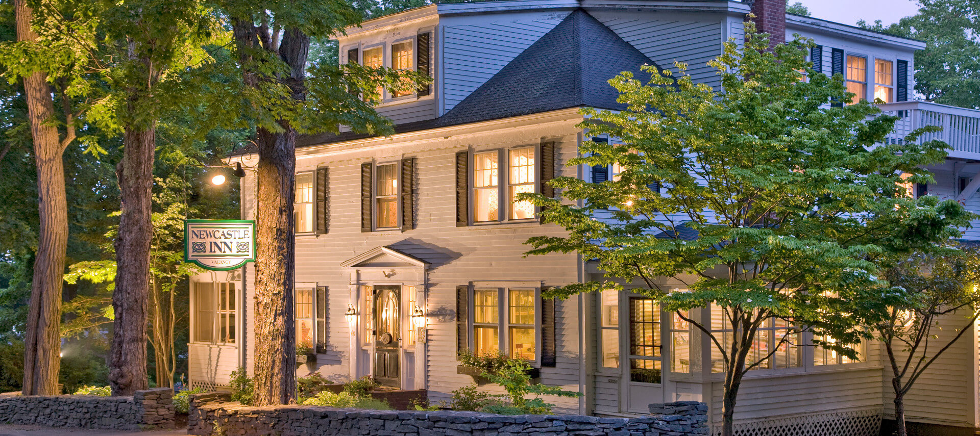 Imposing white two-story mansion lit up at dusk.