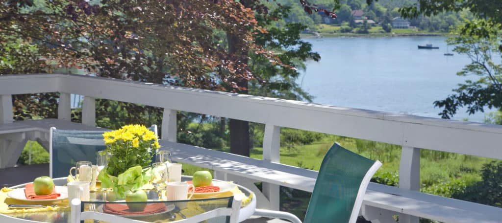 Small table and chairs set for two on deck overlooking the water.