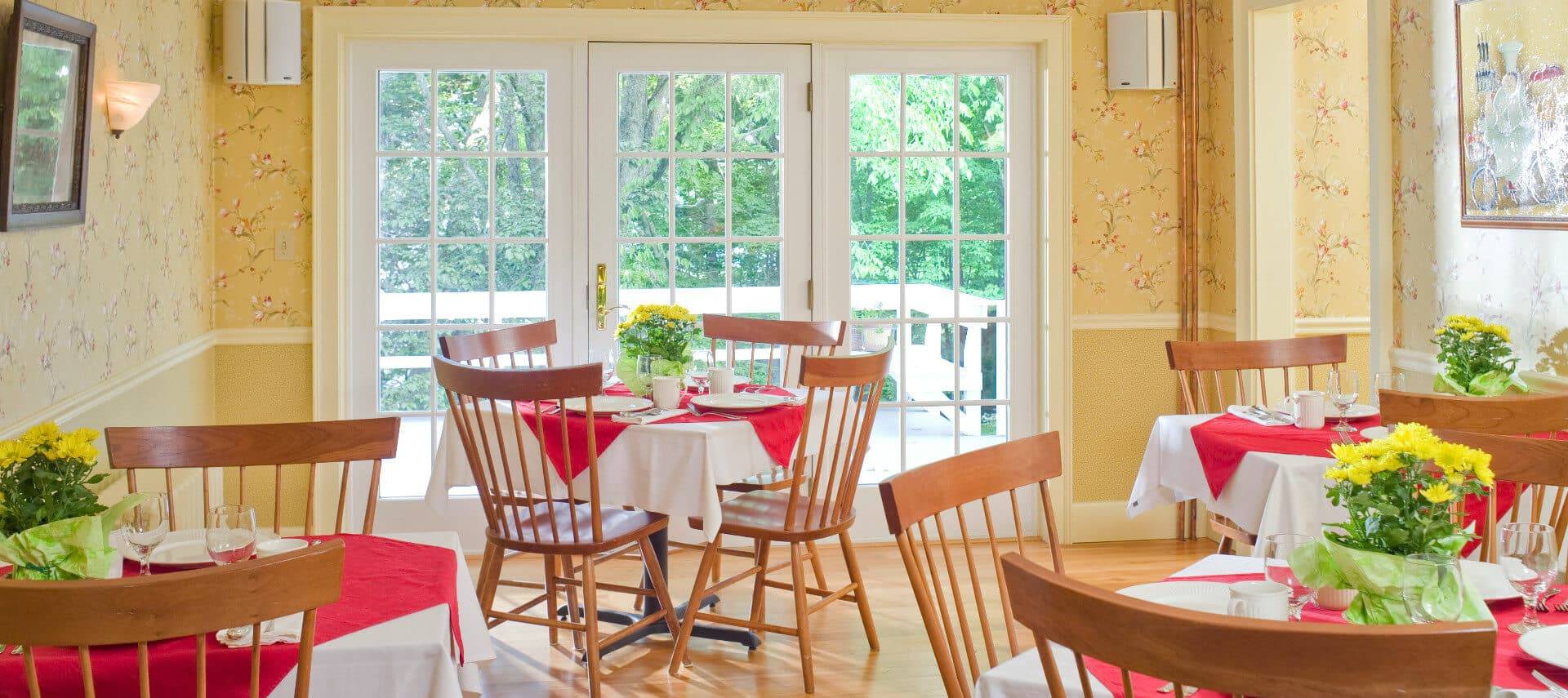 Bright light streams through French doors into dining room with tables and chairs set for four